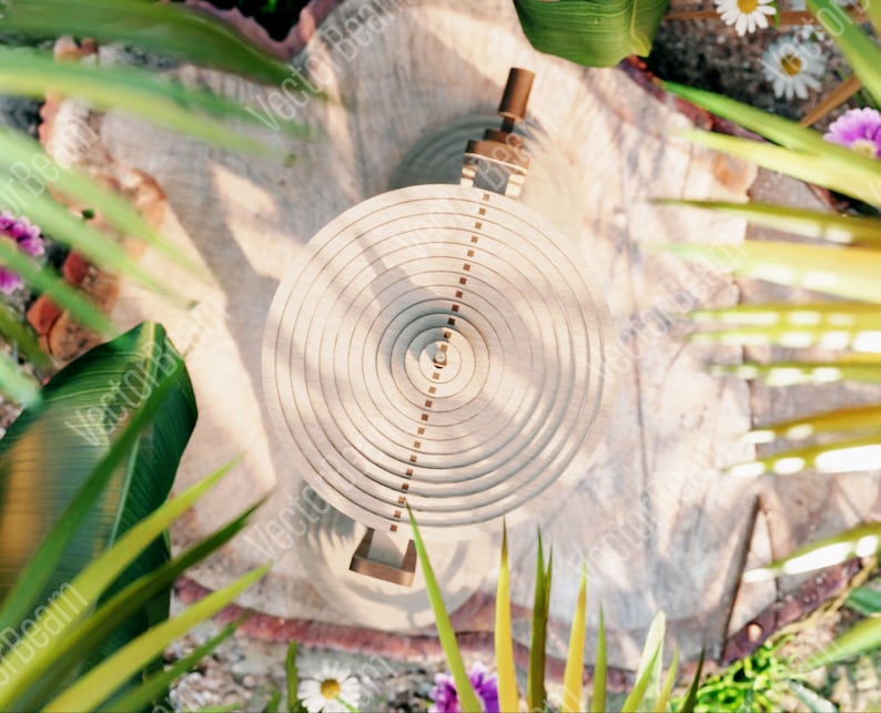 May include: A circular wooden object with concentric rings and a small metal piece in the centre. The object is surrounded by green foliage and flowers.
