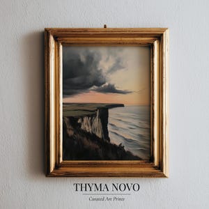 May include: A framed landscape painting depicts a dramatic coastal scene. A high cliff overlooks the ocean under a stormy sky with a golden frame. The text "THYMA NOVO Curated Art Prints" is at the bottom.