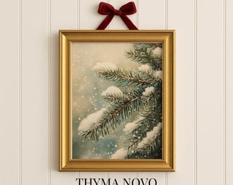 May include: A framed art print featuring a snow-covered evergreen branch. The gold frame is suspended by a burgundy velvet bow. The print has a winter theme, with falling snow and a soft, blue-toned background. The text "THYMA NOVO" and "Curated Art Prints" are at the bottom.