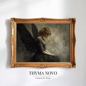 May include: A framed art print featuring a woman with dark angel wings, dressed in a dark gown, and seated in a contemplative pose. The artwork is set against a muted, cloudy background and framed in an ornate gold frame. The text "THYMA NOVO" and "Curated Art Prints" are at the bottom.