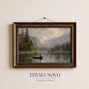 May include: A framed landscape painting depicts a serene lake scene with a person fishing from a small boat. The artwork features a mountain range, trees, and a cloudy sky. The frame is a dark gold color. The text "THYMA NOVO" and "Curated Art Prints" are at the bottom.