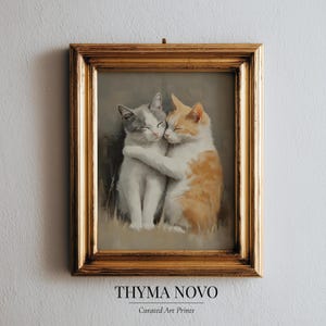 May include: A framed art print featuring two hugging cats. One cat is white and gray, the other is orange and white. The artwork is in a gold frame and has the text "THYMA NOVO Curated Art Prints" at the bottom.
