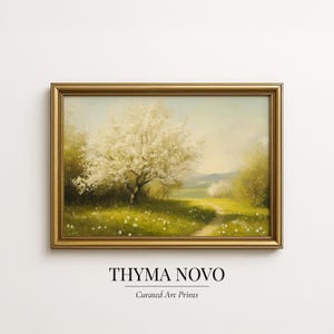 May include: A framed landscape painting featuring a blossoming tree in a field with a path. The artwork has a gold frame and a soft color palette of greens, yellows, and whites. The text "THYMA NOVO" and "Curated Art Prints" is at the bottom.