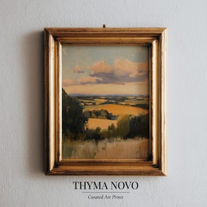 May include: A framed landscape painting with a gold-colored ornate frame. The artwork depicts a rural scene with fields, trees, and a cloudy sky. The painting has a warm color palette with yellows, greens, and blues. The text "THYMA NOVO" and "Curated Art Prints" is at the bottom.