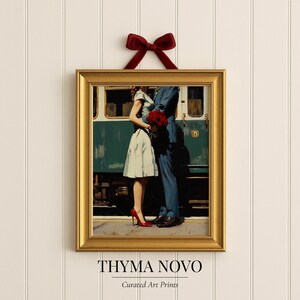 May include: Framed art print featuring a couple embracing in front of a train. The woman wears a light blue dress and red heels, while the man is in a blue suit. A bouquet of red roses is held by the man. The print is in a gold frame and has a maroon ribbon.