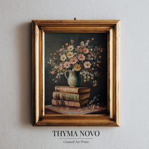 Può includere: Dipinto con cornice di natura morta con un bouquet di fiori in un boccale di ceramica su una pila di libri. Il dipinto ha uno sfondo scuro ed è racchiuso in una cornice dorata ornata. Il testo "THYMA NOVO" e "Curated Art Prints" è in basso.