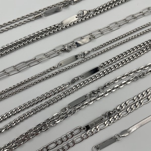 May include: A collection of silver chains with small rectangular name tags. The name tags have different engravings, including the date "08 2022".