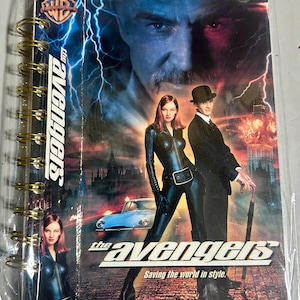 May include: A spiral-bound notebook featuring the movie poster for "The Avengers." The cover art showcases actors Ralph Fiennes, Uma Thurman, and Sean Connery. The title is prominently displayed, along with the tagline "Saving the world in style."