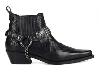 May include: Black leather ankle boots with a pointed toe and a decorative chain and lock detail. The boots have a snakeskin pattern and a silver buckle with a floral design.