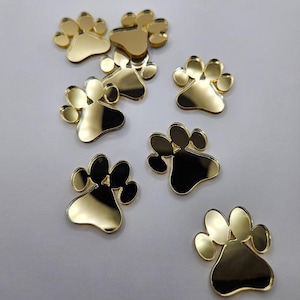 Op de afbeelding: Tien goudkleurige, paw print-vormige acryl spiegeltegels. De tegels zijn ongeveer 2,5 cm in diameter.