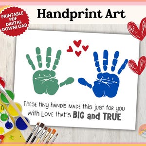 Peut inclure: Carte d'art d'empreintes de mains imprimable avec deux empreintes de mains en vert et bleu, entourées de cœurs rouges. Le texte dit "THESE TINY HANDS MADE this just for YOU with LOVE that's BIG and TRUE".
