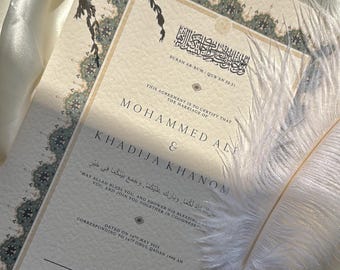May include: A wedding certificate with ornate borders and Arabic script, featuring the names Mohammed Ali & Khadija Khanom. A white feather pen rests on the document, with dried lavender sprigs in the background.