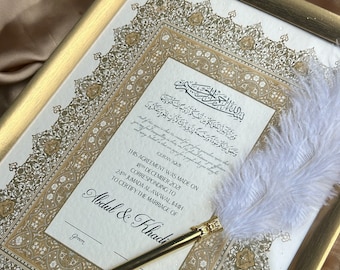 May include: A framed Islamic marriage certificate with gold calligraphy and ornate borders. The certificate is signed "Abdul & Khadi" and includes the date "18th December 2021". A white feather pen is resting on the certificate.