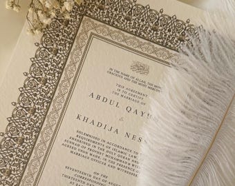 May include: A wedding certificate with ornate gold borders and Arabic calligraphy. The text reads "In the name of Allah, the most gracious and the most merciful." The certificate is for the marriage of Abdul Qayum and Khadija Ness. The ceremony took place on August 17, 2023 at East London Mosque in the United Kingdom.