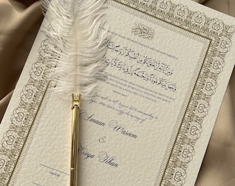 May include: A white feather pen rests on a cream-colored wedding invitation with gold calligraphy. The invitation features an Arabic inscription and the text "as made on 18th August 2024 corresponding to Safar, 1446 AH to certify the marriage of Amaan Waseem & Coya Khan".
