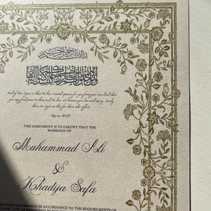 May include: A gold and white wedding certificate with ornate floral borders. The text reads "This agreement is to certify that the marriage of Muhammad Ali & Kohadija Safa has been solemnised in accordance to the requirements of Islamic law, as enshrined in the Holy Quran and the Sunnah of Prophet Muhammad (SAW) with the agreed upon mahr, in the presence of the marriage officer and witnesses. Saturday 13 January 2024 Corresponding to 1445ah"