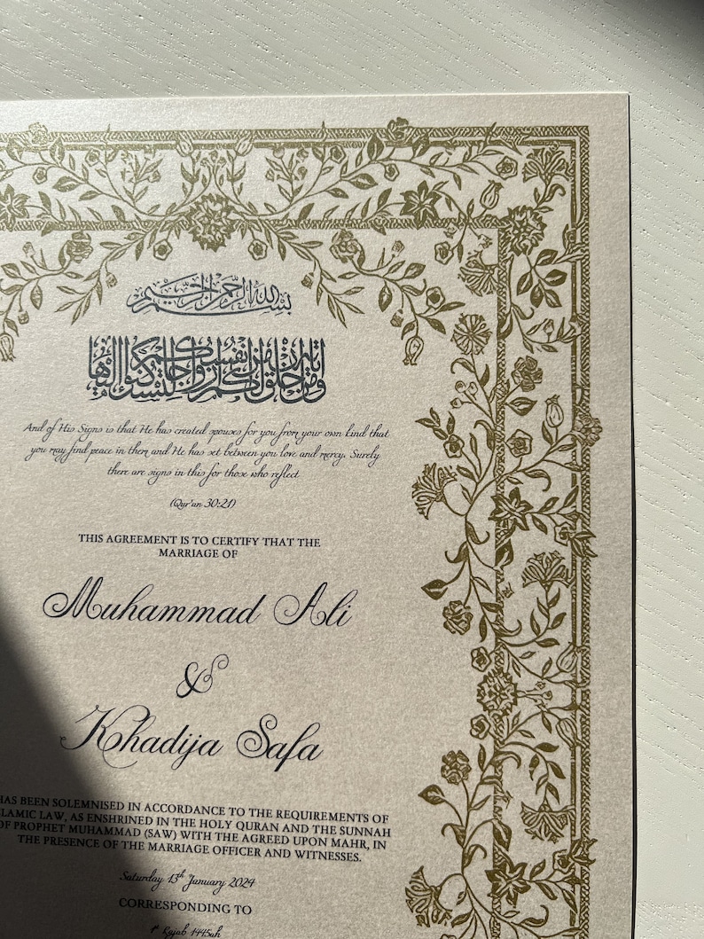 May include: A gold and white wedding certificate with ornate floral borders. The text reads "This agreement is to certify that the marriage of Muhammad Ali & Kohadija Safa has been solemnised in accordance to the requirements of Islamic law, as enshrined in the Holy Quran and the Sunnah of Prophet Muhammad (SAW) with the agreed upon mahr, in the presence of the marriage officer and witnesses. Saturday 13 January 2024 Corresponding to 1445ah"