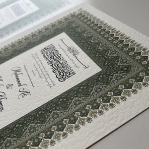 Peut inclure: Une carte blanche avec une bordure verte et un motif complexe. La carte pr&eacute;sente de la calligraphie arabe et le texte "Mohammed Ali & Khadija Khanom 14 mai 2023 F&eacute;licitations".