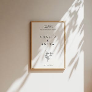 Peut inclure: Une impression de mariage minimaliste avec une illustration florale et le texte "Et Nous Vous Avons Cr&eacute;&eacute;s Par Paires" en &eacute;criture arabe. Les noms "Khalid & Anisa" et la date "18 juin 2024" sont &eacute;galement inclus.