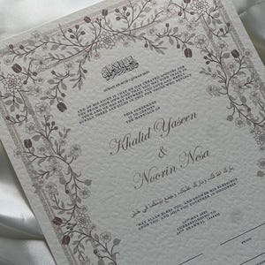 Puede incluir: Un certificado de boda con borde floral en tonos grises y marrones. El documento incluye escritura &aacute;rabe y texto en ingl&eacute;s, con los nombres Khalid Yaseen y Noorin Nesa. La fecha es el 14 de mayo de 2023.
