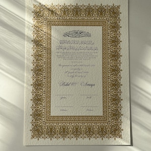 Peut inclure: Un certificat encadr&eacute; d'or avec une inscription arabe et du texte en anglais. Le certificat est pour une c&eacute;r&eacute;monie de mariage et comprend les noms Bilal et Amaya. Le texte dit "Et parmi Ses signes, Il vous a cr&eacute;&eacute;s de vous-m&ecirc;mes des &eacute;pouses pour que vous trouviez en elles la qui&eacute;tude, et Il a mis entre vous de l'affection et de la mis&eacute;ricorde. En cela, il y a des signes pour un peuple qui r&eacute;fl&eacute;chit (Coran 30:21)"