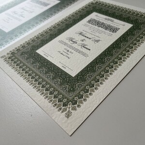 Peut inclure: Un certificat de mariage blanc avec une bordure verte orn&eacute;e d'un motif g&eacute;om&eacute;trique complexe. Le certificat indique "Muhammad Ali & Khadija Khanum" et la date "14 juillet 2013 (1er Jamadi 1434)".