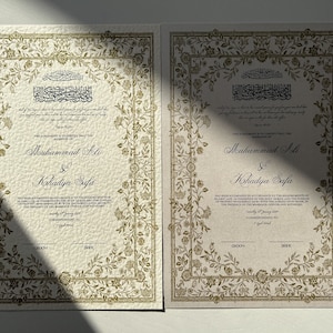 May include: Two ivory-coloured wedding certificates with gold floral borders. The text reads "This Agreement is to Certify that the Marriage of Muhammad Ali & Khadidja Safa has been solemnized in accordance with the Religious Rites of Prophet Muhammad (SAW) with the Holy Quran and Sunnah in the presence of the Marriage Officer and Witnesses.  Saturday 8th January 2017. Corresponding to 7th Jumada Al-Awwal 1438."