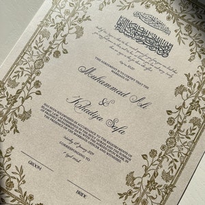 May include: A formal marriage certificate with a gold floral border and Arabic calligraphy. The text reads "This agreement is to certify that the marriage of Muhammad Ali & Khadija Safa has been solemnised in accordance to the requirements of Islamic law, as enshrined in the Holy Quran and the Sunnah of Prophet Muhammad (SAW) with the agreed upon mahr, in the presence of the marriage officer and witnesses. Saturday 13 January 2029 corresponding to Rajab 1441".