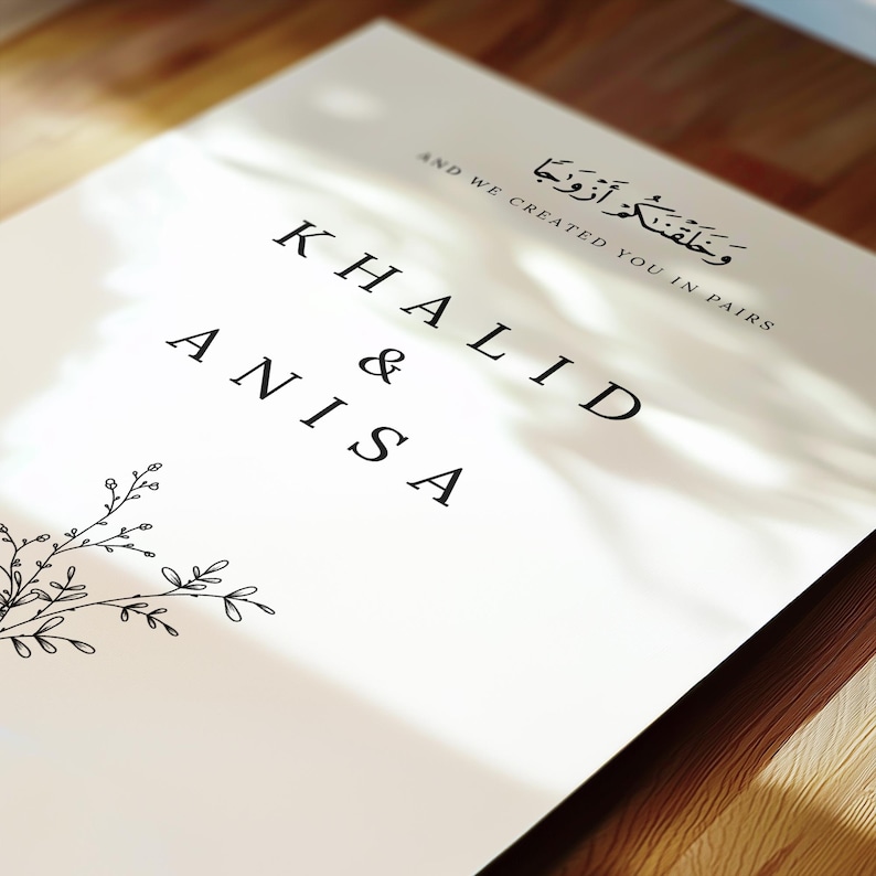 Peut inclure: Une invitation de mariage blanche avec une calligraphie noire qui dit "Khalid & Anisa" et le texte arabe "وَخَلَقْنَاكُمْ أَزْوَاجًا" qui se traduit par "Et Nous vous avons cr&eacute;&eacute;s en couples".