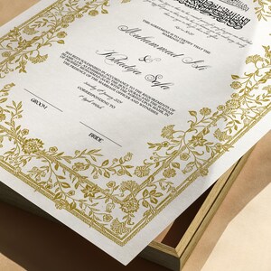 Może przedstawiać: Biały akt ślubny z złotymi kwiatowymi obramowaniami i tekstem "This agreement is to certify that the marriage of Muhammad Ali & Khadija Safa has been solemnised in accordance to the requirements of Islamic law, as enshrined in the Holy Quran and the Sunnah of Prophet Muhammad (SAW) with the agreed upon mahr, in the presence of the marriage officer and witnesses. Saturday 15 January 2024 Corresponding to 1 Jumad Al-Thani 1445".