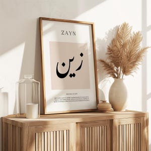 May include: A framed vertical wall art print featuring the name ZAYN in English and Arabic script, centered on a light beige square. The text below explains the meaning of the name, emphasizing beauty, elegance, grace, and perfection.