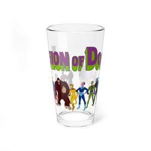 Op de afbeelding: Een helder glas met een cartoonillustratie van een superheldenteam. Het glas heeft de woorden "ION of DOOM" in paars en groen. De personages zijn onder meer een gorilla, een cheetah en andere kostuumfiguren.