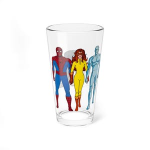 May include: A clear glass featuring comic book characters Spider-Man, a woman in a yellow suit, and a blue-skinned character. The characters are in full color and are standing together. The glass is cylindrical and has a wide base.