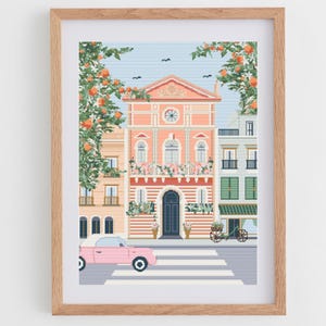 Puede incluir: Una impresión artística enmarcada que presenta una colorida ilustración de una escena de calle europea. La obra de arte representa edificios en tonos melocotón, amarillo y verde, con un coche rosa en un paso de cebra. Naranjos y un cielo azul completan la escena.