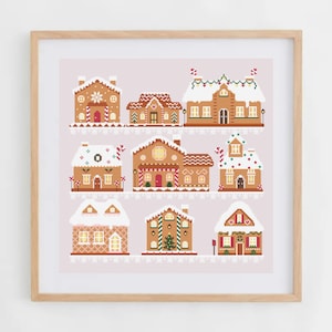 May include: A framed print featuring nine gingerbread houses in a cross-stitch style. Each house has unique details like snow-covered roofs, candy cane accents, and festive decorations. The houses are set against a light pink background.