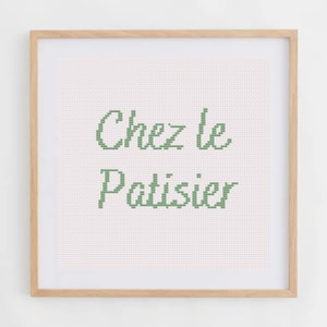 Peut inclure: Une broderie au point de croix encadrée avec un fond blanc et un texte vert qui dit "Chez le Patissier".