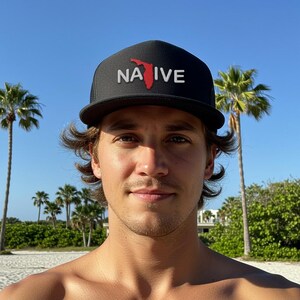 May include: A person wearing a black mesh trucker hat with a red outline of the state of Florida and the word "NATIVE" in white letters.