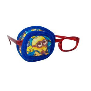 Könnte beinhalten: Ein blaues Augenpflaster mit einem Minion-Charakterdruck, befestigt an einer roten Brille.
