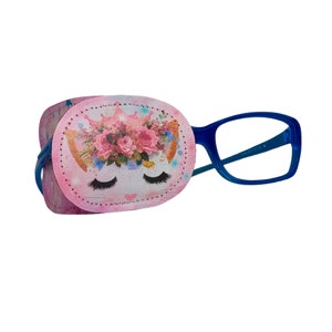 Peut inclure: Une paire de lunettes à monture bleue avec un cache-œil attaché. Le cache-œil rose présente un motif de licorne avec une couronne florale et des cils fermés. Le cache-œil est conçu pour s'adapter à la lentille gauche.