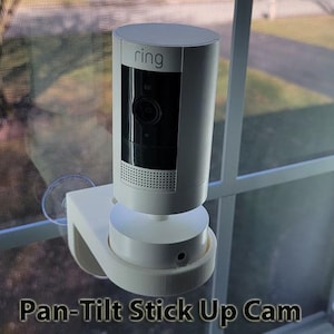 May include: A white Ring Pan-Tilt Stick Up Cam mounted on a window with a white background. The camera has a black lens and the word "ring" printed on the front.