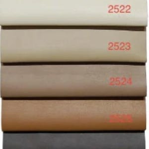 May include: A color swatch display featuring samples of fabric in various shades. The samples range from white to black, with each color labeled with a number. The top of the display has the "Top textil" logo.