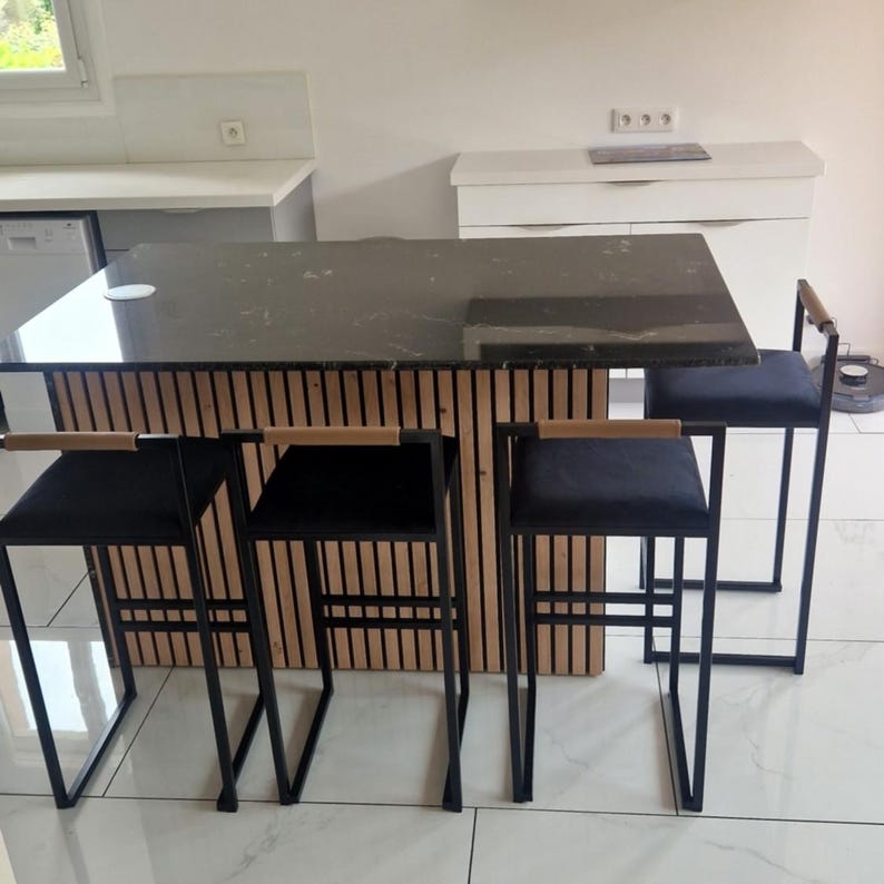 May include: A modern kitchen island with a dark gray countertop and a wooden slatted base. Three black bar stools with black seats and wooden armrests are positioned around the island. The stools have a black metal frame.