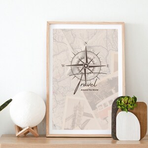 Puede incluir: Una impresión enmarcada con una brújula y la palabra "travel" escrita en cursiva. La impresión tiene un fondo de mapa vintage con imágenes de monumentos como la Torre Eiffel y el Big Ben. El texto debajo de la brújula dice "Around The World".