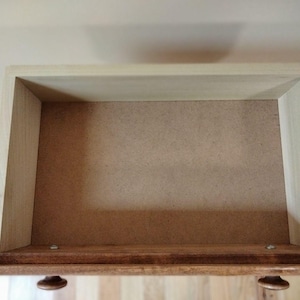 May include: Empty wooden drawer with a light brown interior. The drawer is open and the inside is visible.