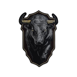 May include: A shield-shaped patch featuring a detailed black and white illustration of a charging bull with golden horns and glowing yellow eyes. The design is framed by a thin gold border against a solid black background, creating a sharp contrast.