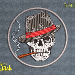Puede incluir: Diseño bordado de una calavera con un fedora y fumando un cigarrillo. La calavera está en un círculo con un fondo gris. El texto "3 SIZES" está en la esquina superior derecha de la imagen.