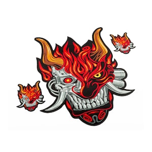 May include: Embroidered patches featuring a demonic oni mask design. The large patch is red, black, and silver, with flames and mechanical details. Two smaller patches and one medium-sized patch are also included, all with the same design.