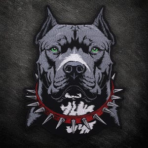 May include: Embroidered patch depicting a pit bull with grey fur, green eyes, and a white snout. The dog is wearing a red collar with silver spikes. The patch is set against a black background.