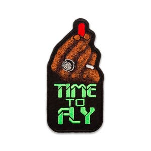 Puede incluir: Parche bordado con una mano marrón con una uña roja y un cigarrillo. El parche tiene las palabras "TIME TO FLY" en letras verdes sobre un fondo negro. El parche es para planchar.