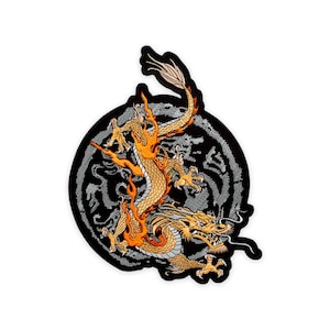 Peut inclure: Un écusson brodé représentant un dragon doré avec des flammes orange s'enroulant sur un fond circulaire gris. Le dragon présente des écailles détaillées, des griffes acérées et une longue queue, le tout souligné par un fil noir sur une bordure noire.